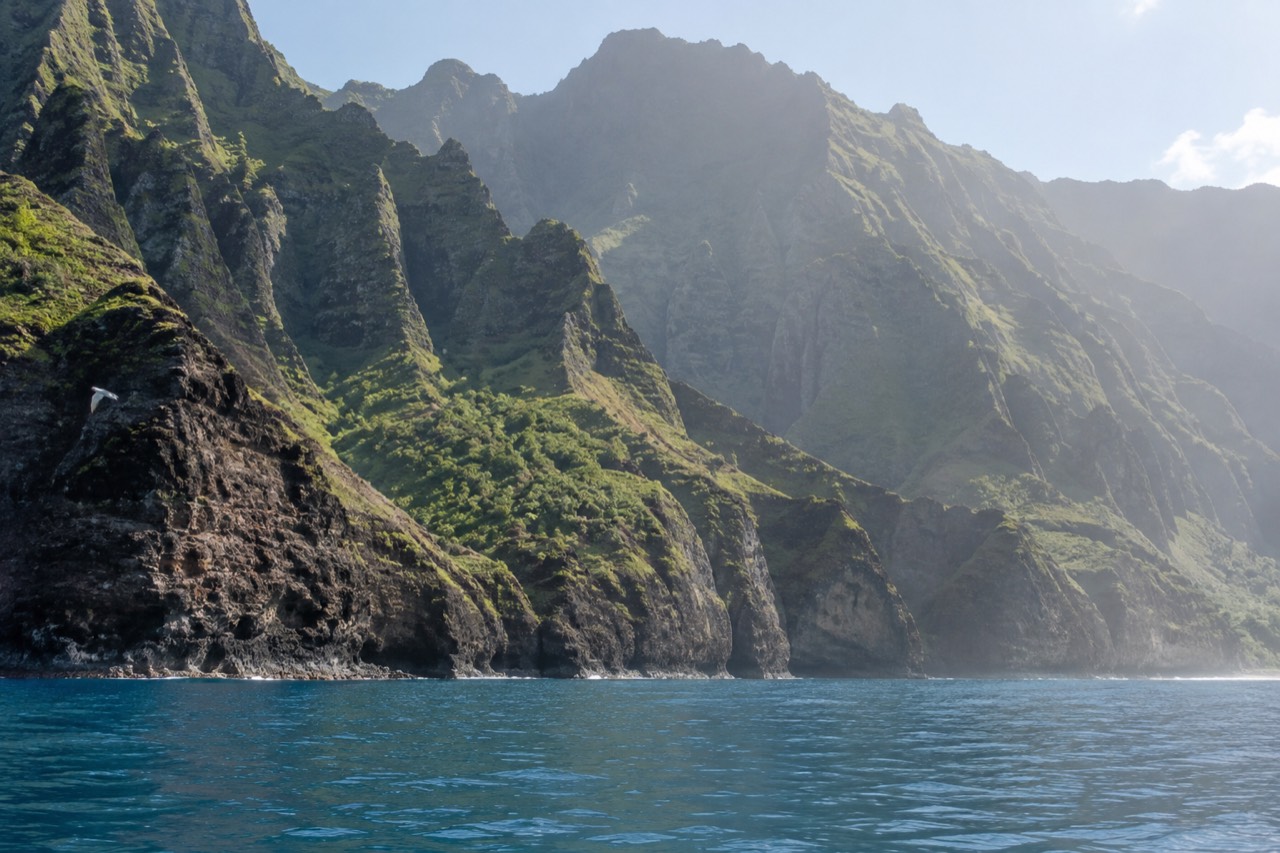 Napali Coast sea cliffs rising from calm blue water along Kauai's northwest shoreline