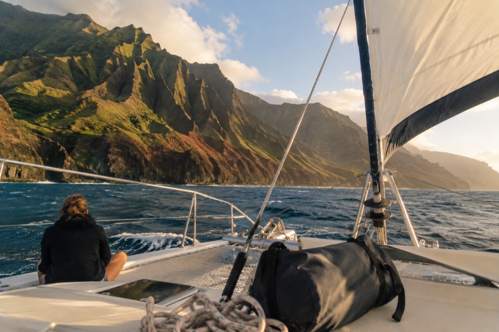 A catamaran under sail along the Napali cliffs in late afternoon light
