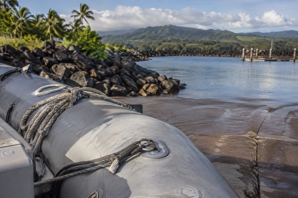 A rigid inflatable raft moored at a small boat harbour on Kauai's west side in morning light