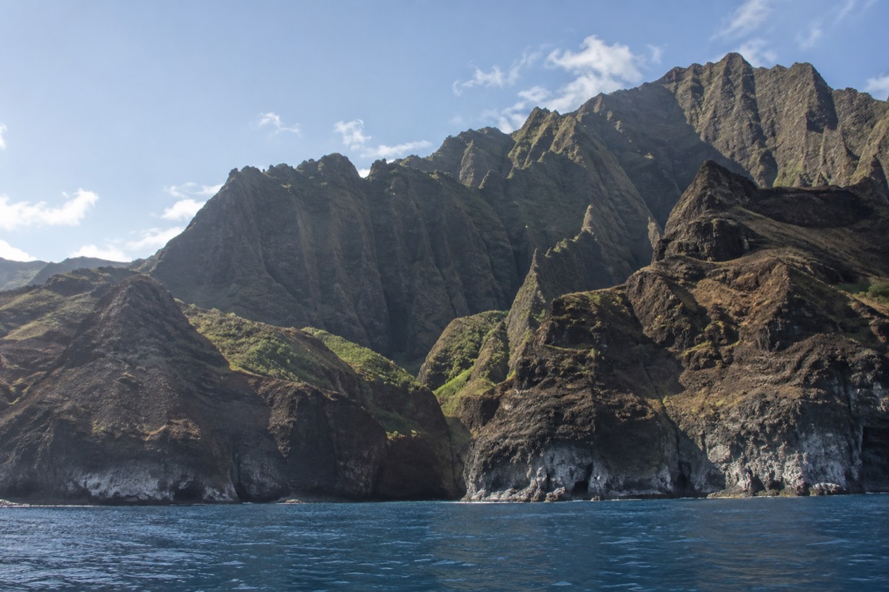 Sea cliffs rising from calm blue water along the Napali Coast of Kauai
