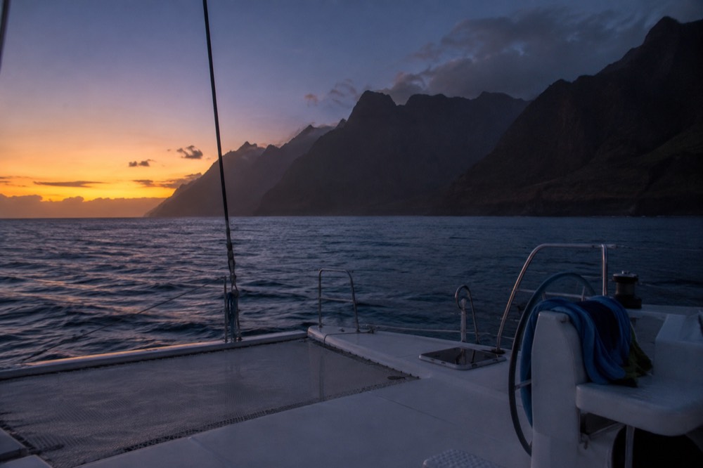 An empty boat deck in blue twilight with the last light on distant sea cliffs