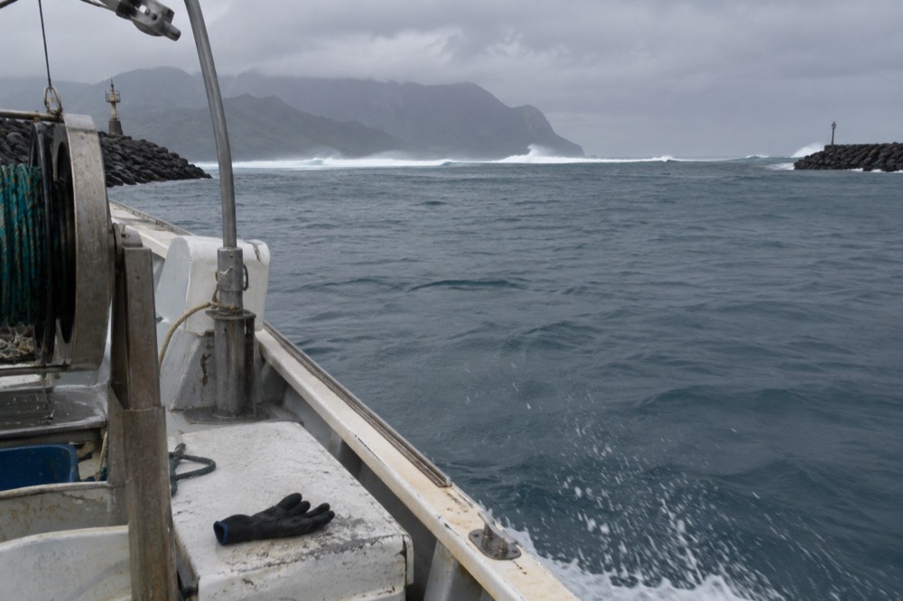 Open ocean swells with a distant island on the horizon under scattered clouds