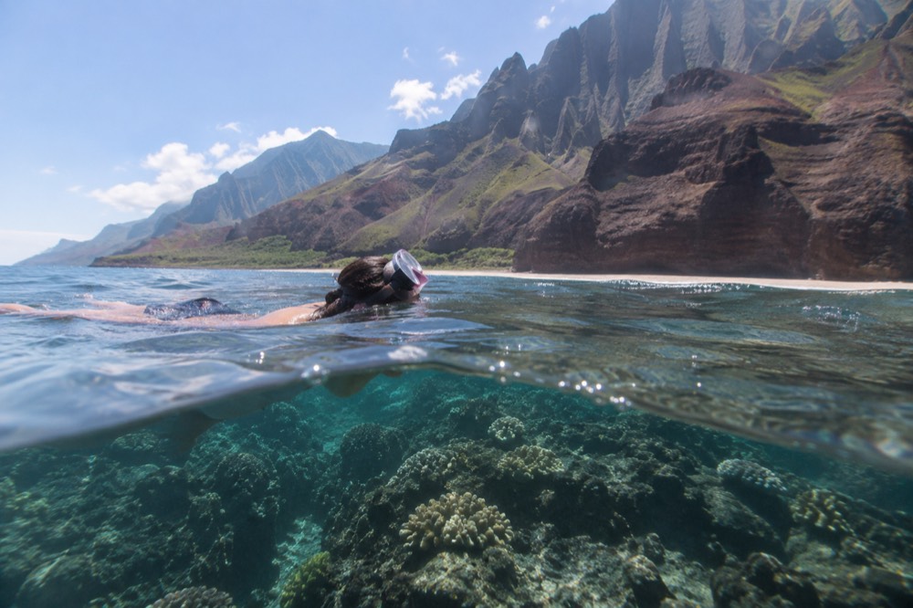 A snorkeler floating above a coral reef in clear blue water