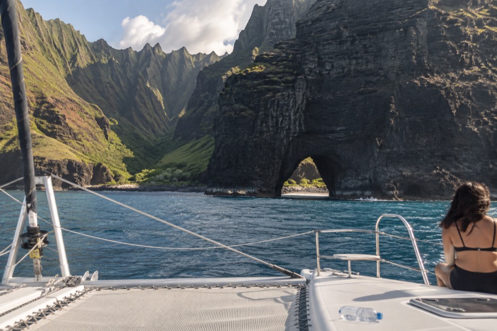 A catamaran at anchor near a Napali Coast snorkel spot with cliffs behind