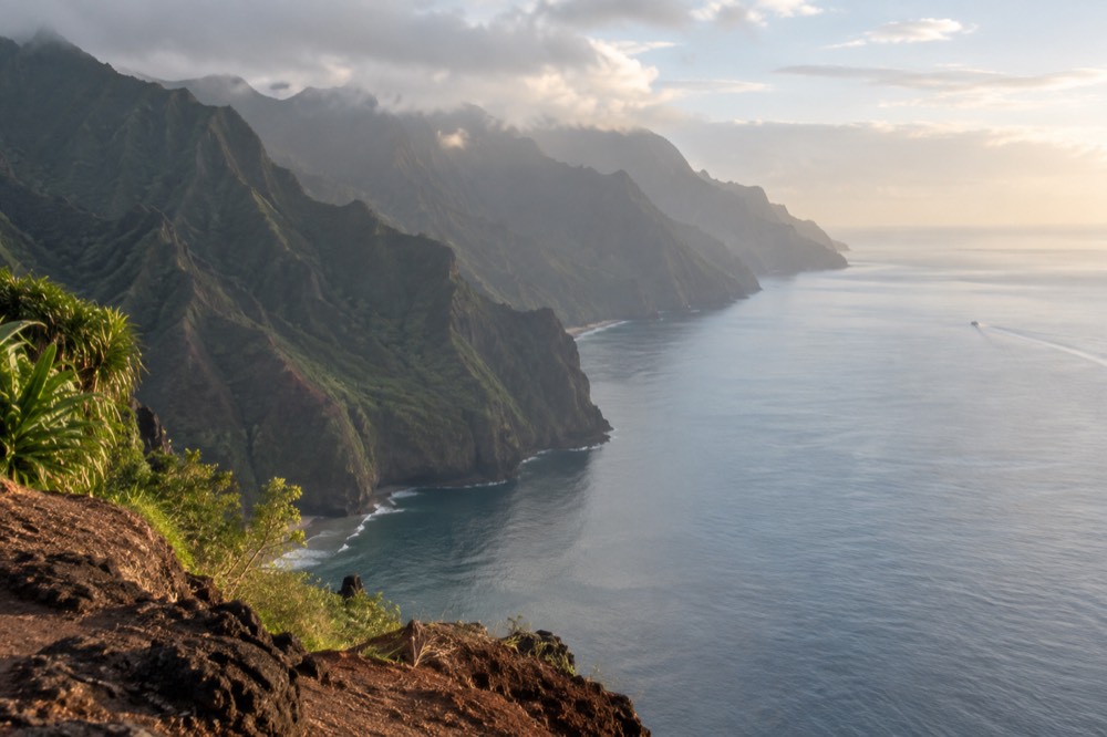 Smooth early morning ocean surface beneath sea cliffs on the Napali Coast