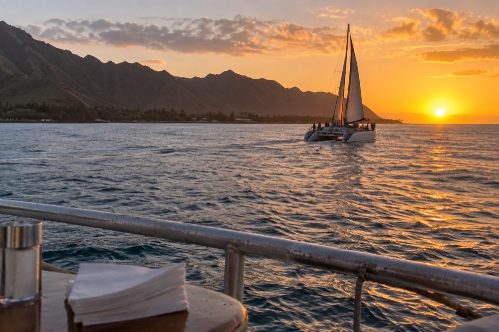 A catamaran under way on open water near the Napali Coast in late day light