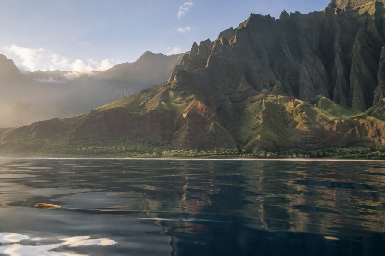 Calm morning water along the green cliffs of the Napali Coast on Kauai