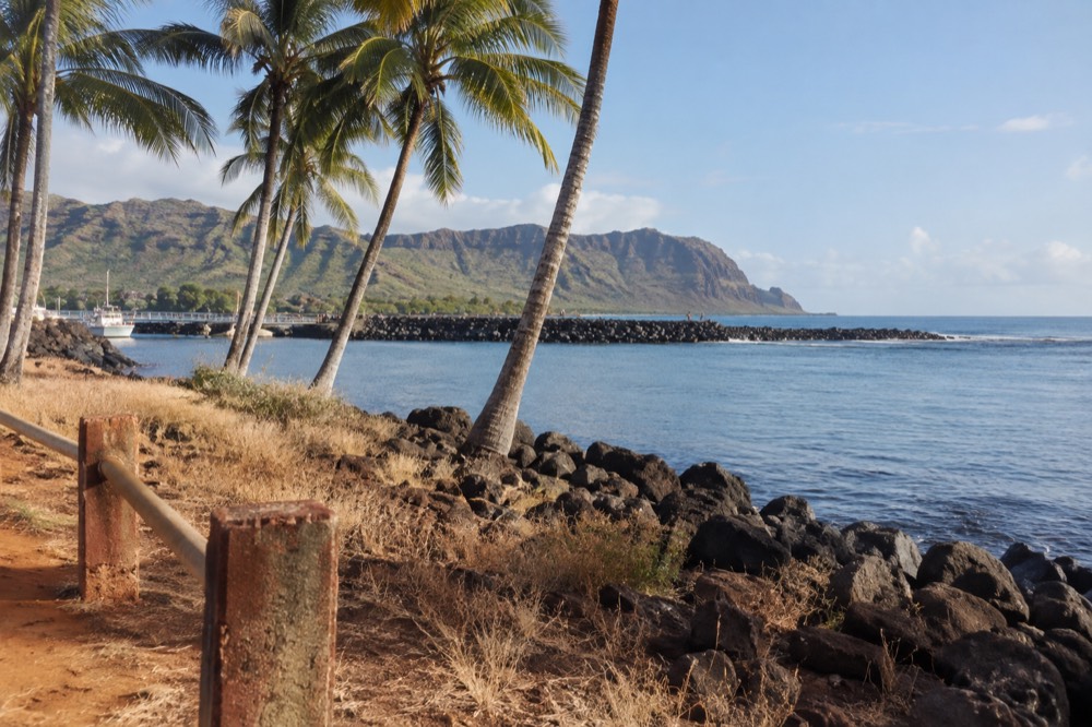 A resort coastline on Kauai's south shore with palm trees and calm water in the morning