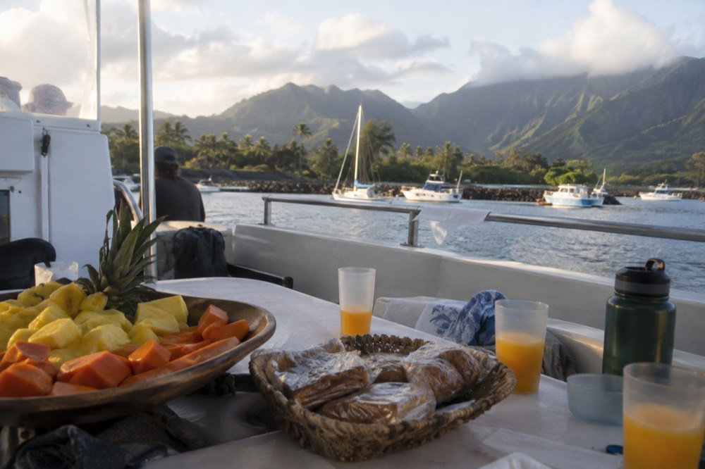 Breakfast spread of fruit and pastries set out on a boat deck table