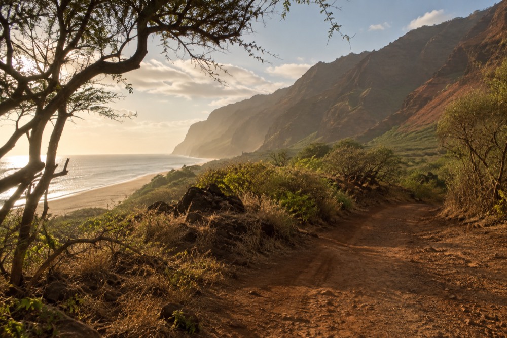 Red and green canyon walls with a winding road and distant ocean view