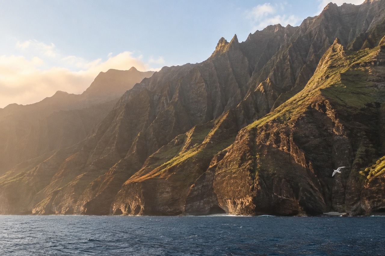 Green sea cliffs of the Napali Coast rising above calm blue water near Kauai