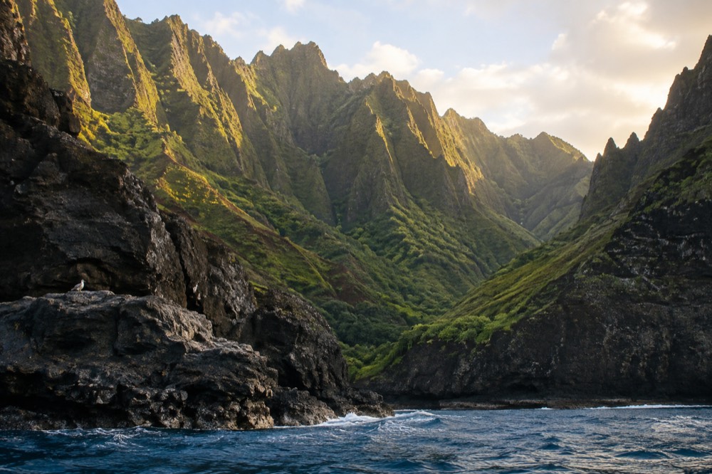 Golden evening light on the ridged cliffs and empty water of the Napali Coast in late afternoon.