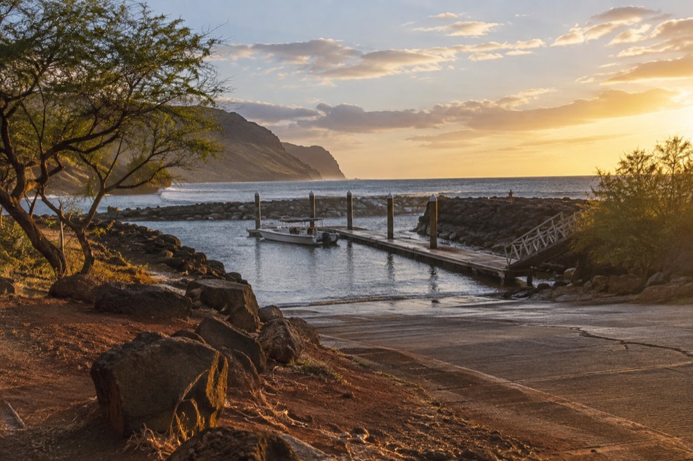 A coastal road curving along dry hills above the sea on Kauai's southwest shore