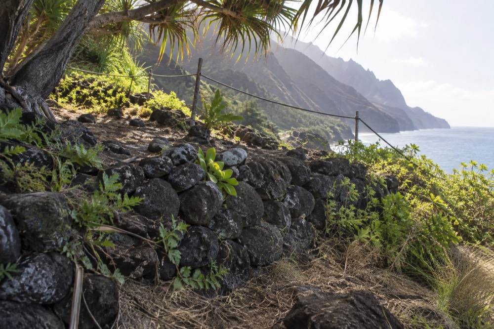 Stone terraces of an ancient Hawaiian archaeological site behind a rope barrier near the shoreline