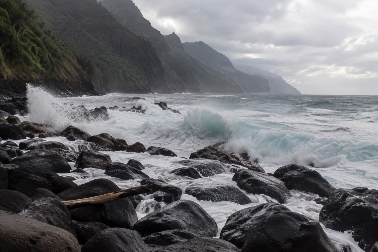 Rough winter surf breaking against a steep coastline under a grey sky
