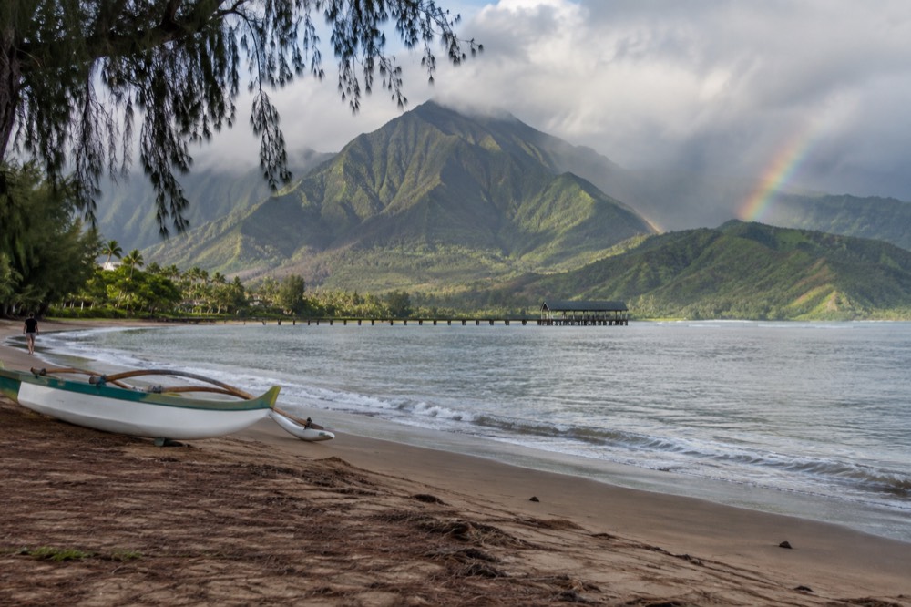 Hanalei Bay with green mountains and a rainbow in the distance