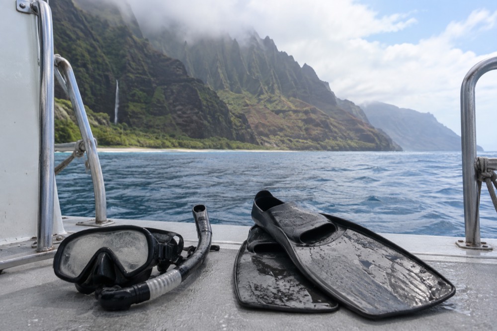 Snorkel mask and fins resting on a boat deck with open water beyond