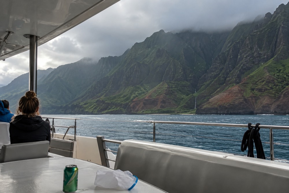 The wide deck of a large power catamaran fills the foreground on Kauai