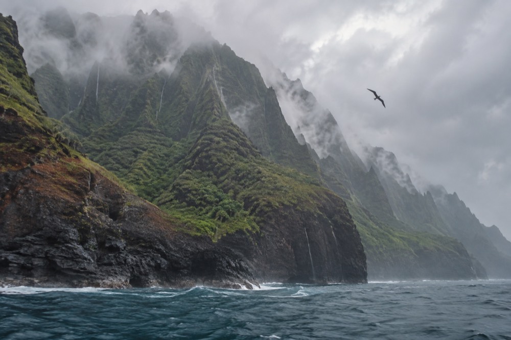 Rain streaks the fluted green Napali cliffs of Kauai