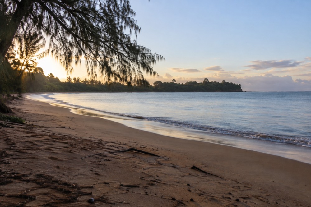 A quiet beach morning with soft light over sand and a calm ocean horizon