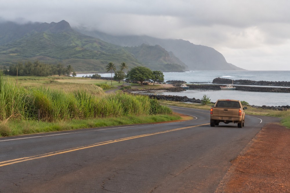 Coastal highway on Kauai's south shore with green hills and ocean in the distance