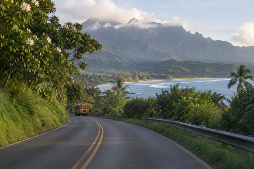 A two-lane coastal highway winding along a green shoreline with ocean beyond.