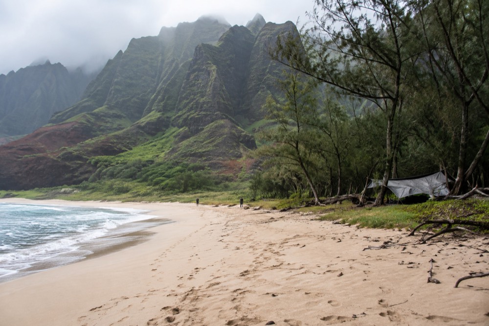 A remote sandy beach at the mouth of a wide valley beneath tall ridges
