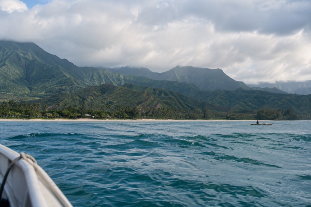 A coastal road curving along green cliffs above the ocean in north Kauai