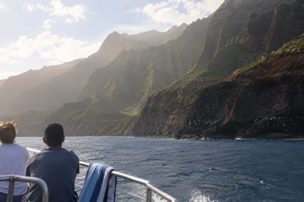 A tour boat crossing open water off Kauai's dry leeward coast with the first sea cliffs appearing ahead
