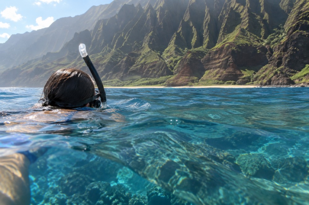 A snorkeler floating above a coral reef in clear blue water