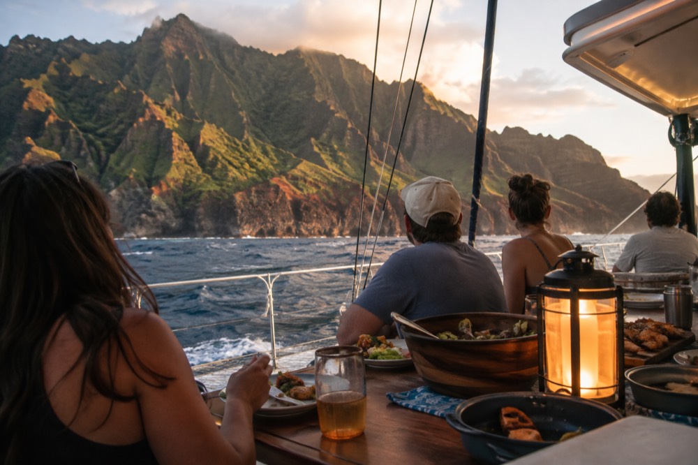 Family-style dinner service on the deck of a sailing catamaran under way off the Napali Coast