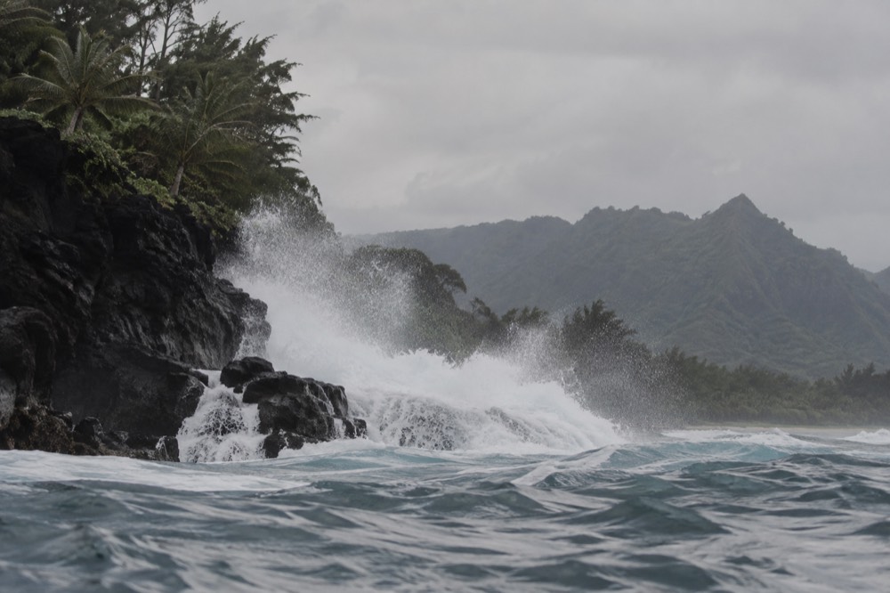Tall winter surf breaking against the cliffs of the Napali Coast in Kauai