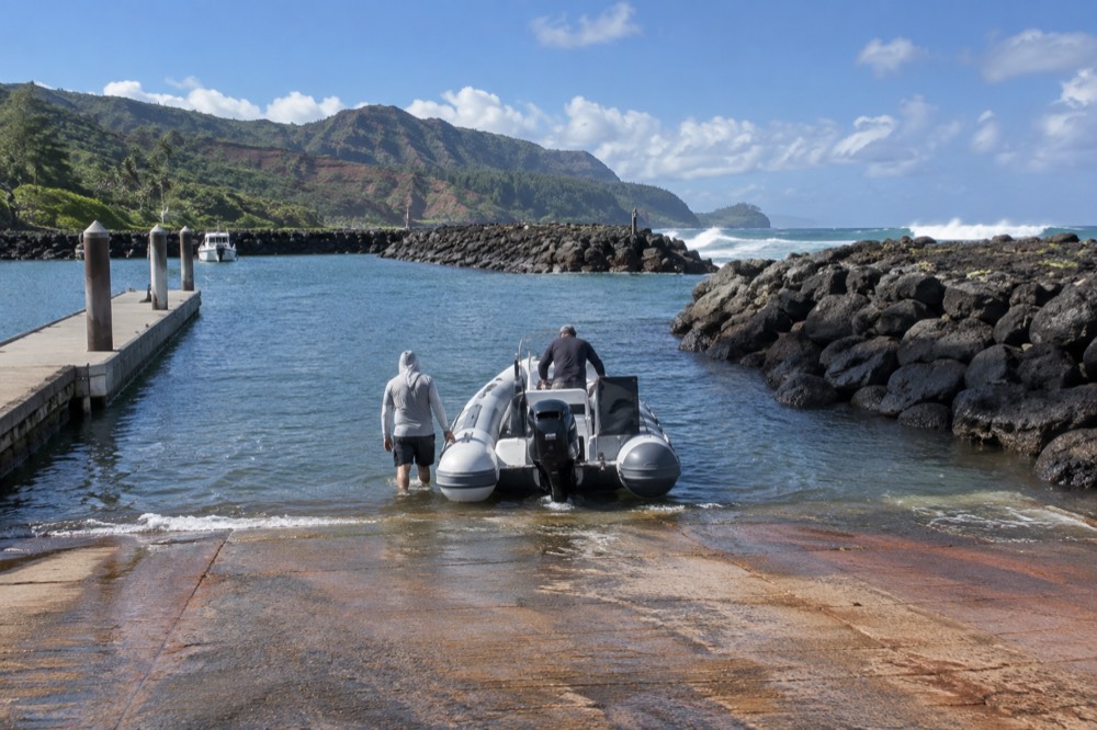 A rigid inflatable raft cruising close to the green sea cliffs of the Napali Coast