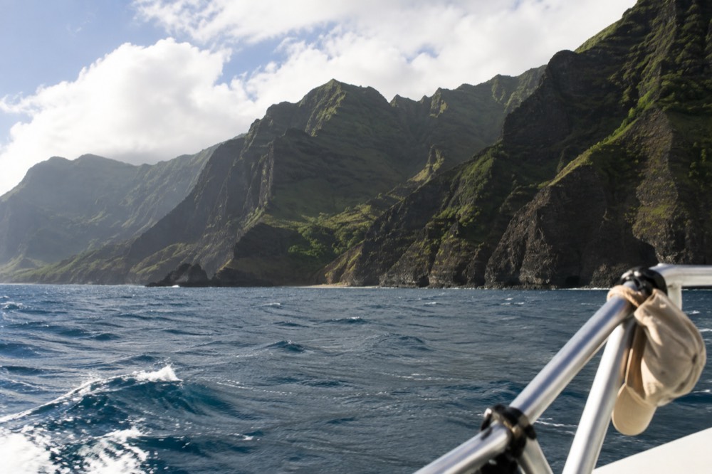 Trade-wind chop flicking whitecaps across calm water below the green Napali cliffs