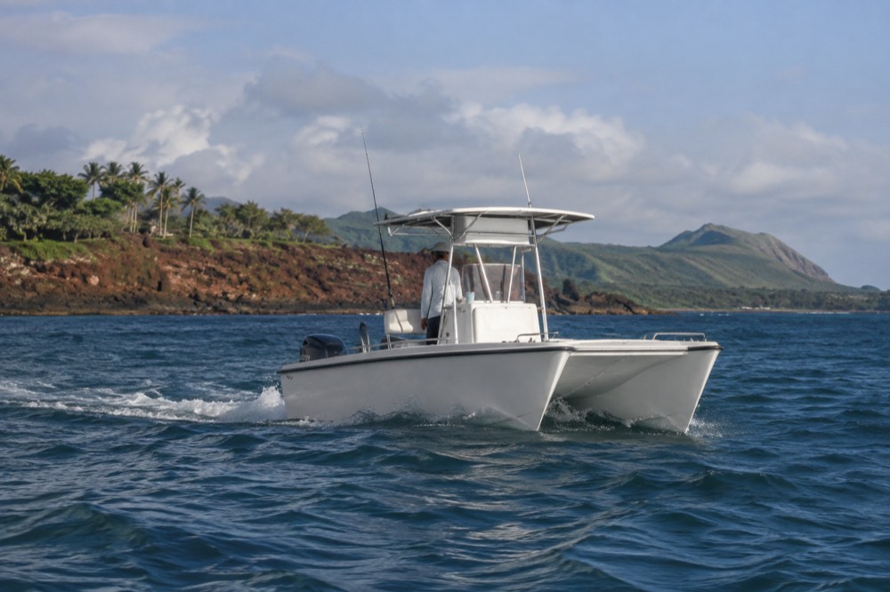 A small power catamaran runs the open water off Kikiaola near Waimea