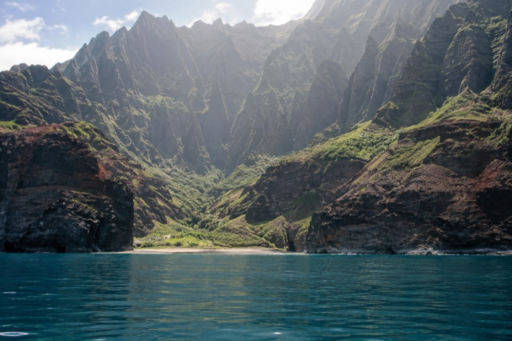 Calm summer ocean along a green Napali valley cliff