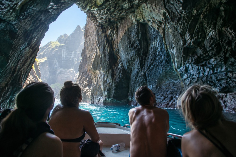 Raft passengers looking up at a cave opening in summer light