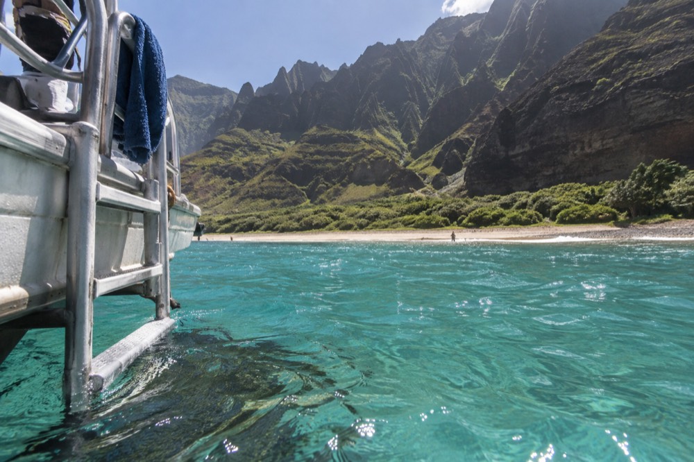 A ladder at the stern of a moored boat with turquoise water below
