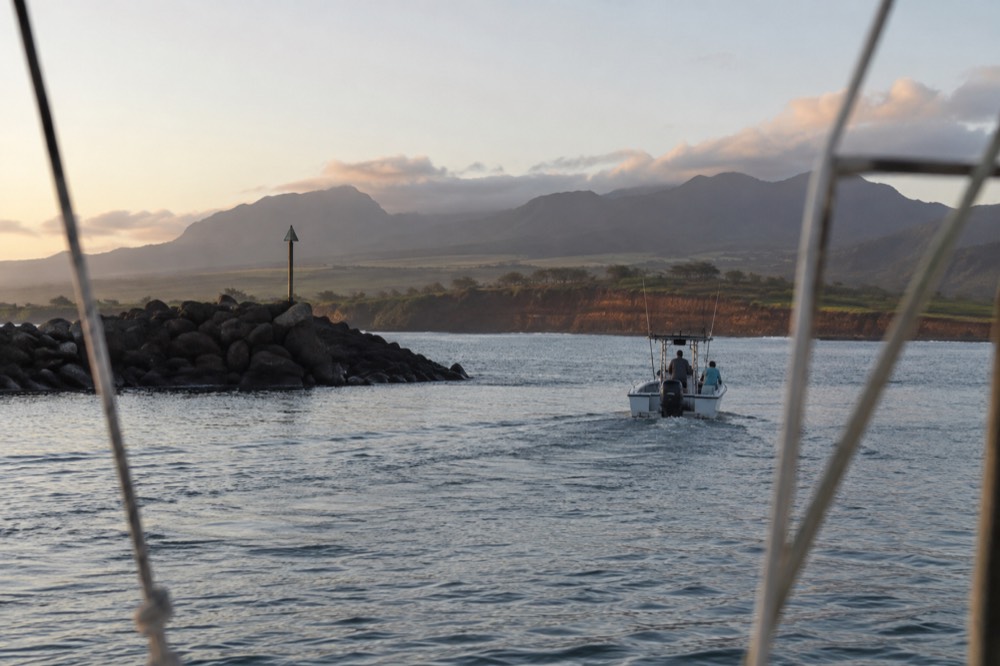 A small boat harbor at dawn with masts and a loading dock along calm water