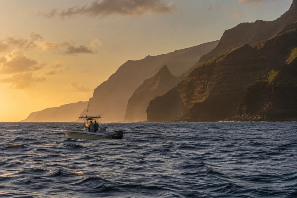 A single permitted raft idles on open swell well clear of Kauai's west shore