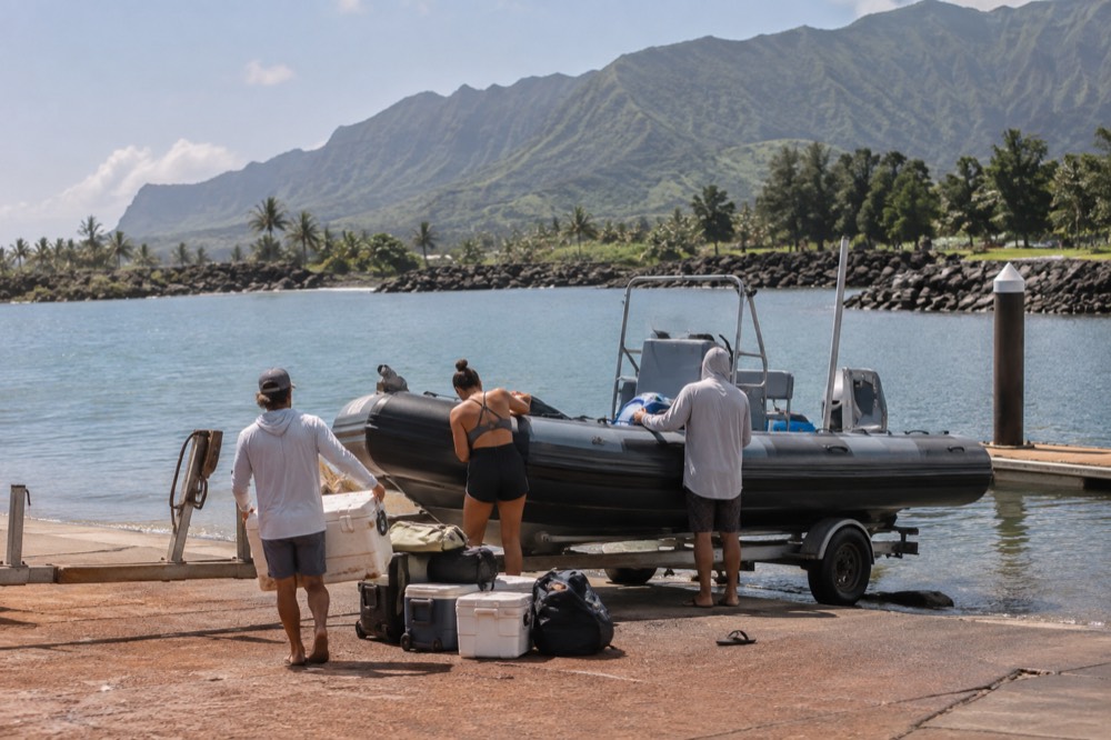 A raft crew loads snack coolers onto a Zodiac-style hull at the Kikiaola ramp near Waimea