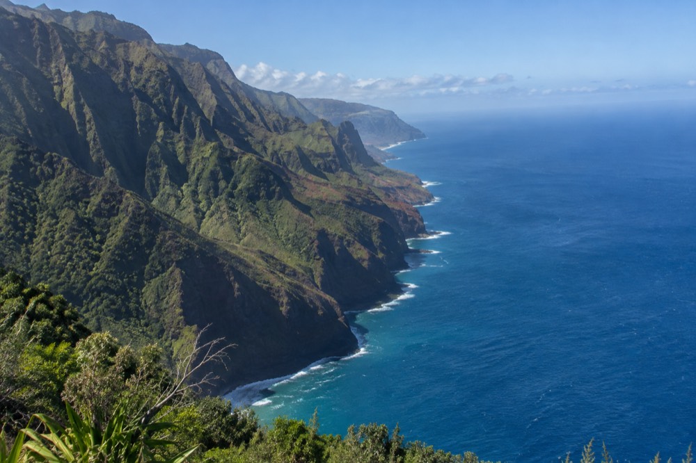 The Napali Coast seen from above, with green cliffs dropping into the blue ocean